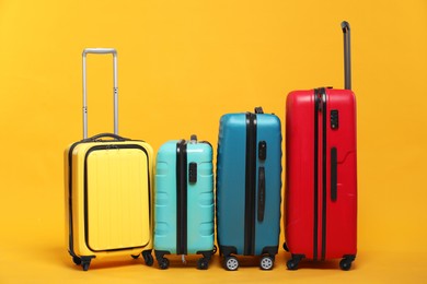 Photo of Many closed colorful suitcases on orange background