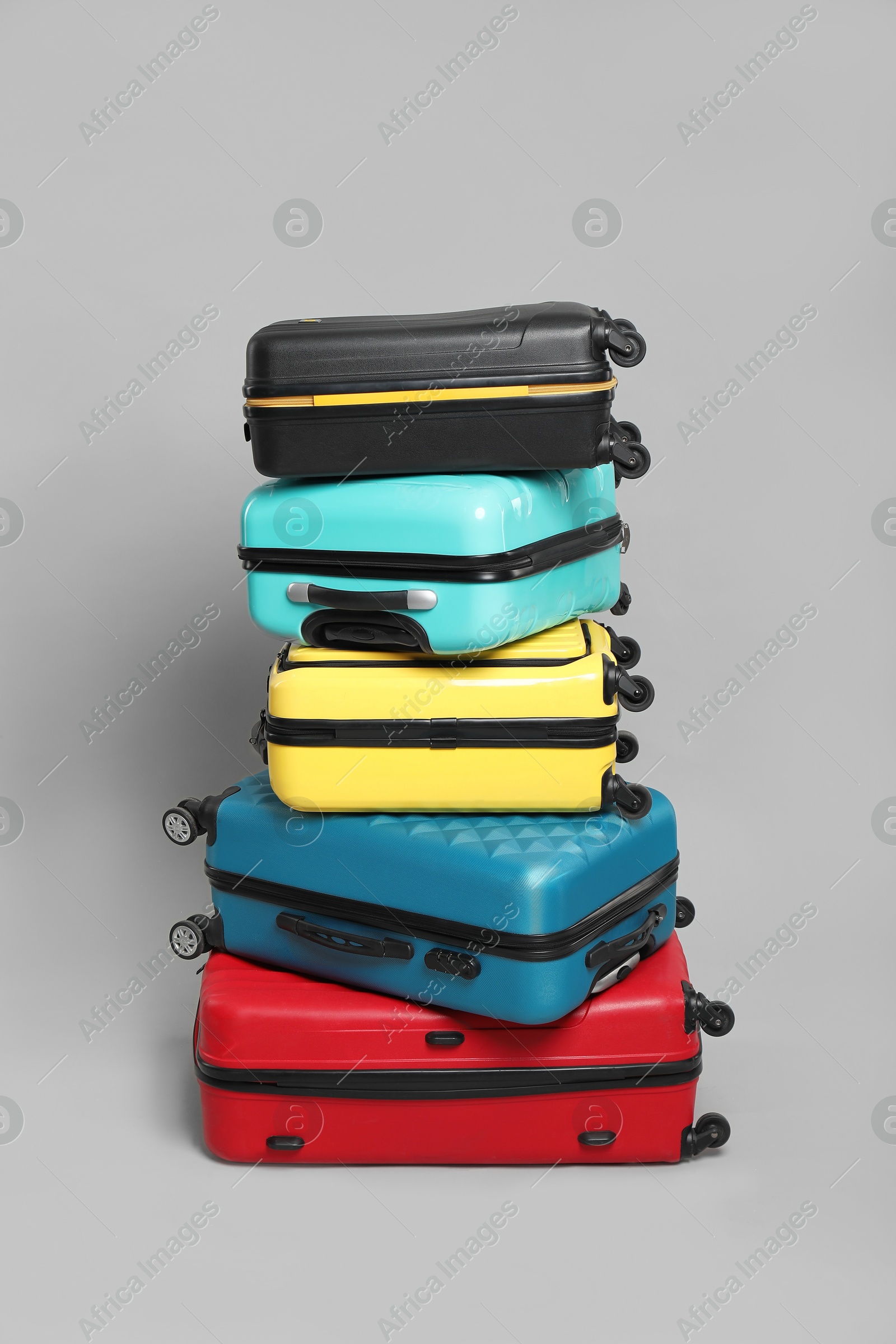 Photo of Stack of colorful suitcases on grey background