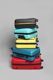 Photo of Stack of colorful suitcases on grey background