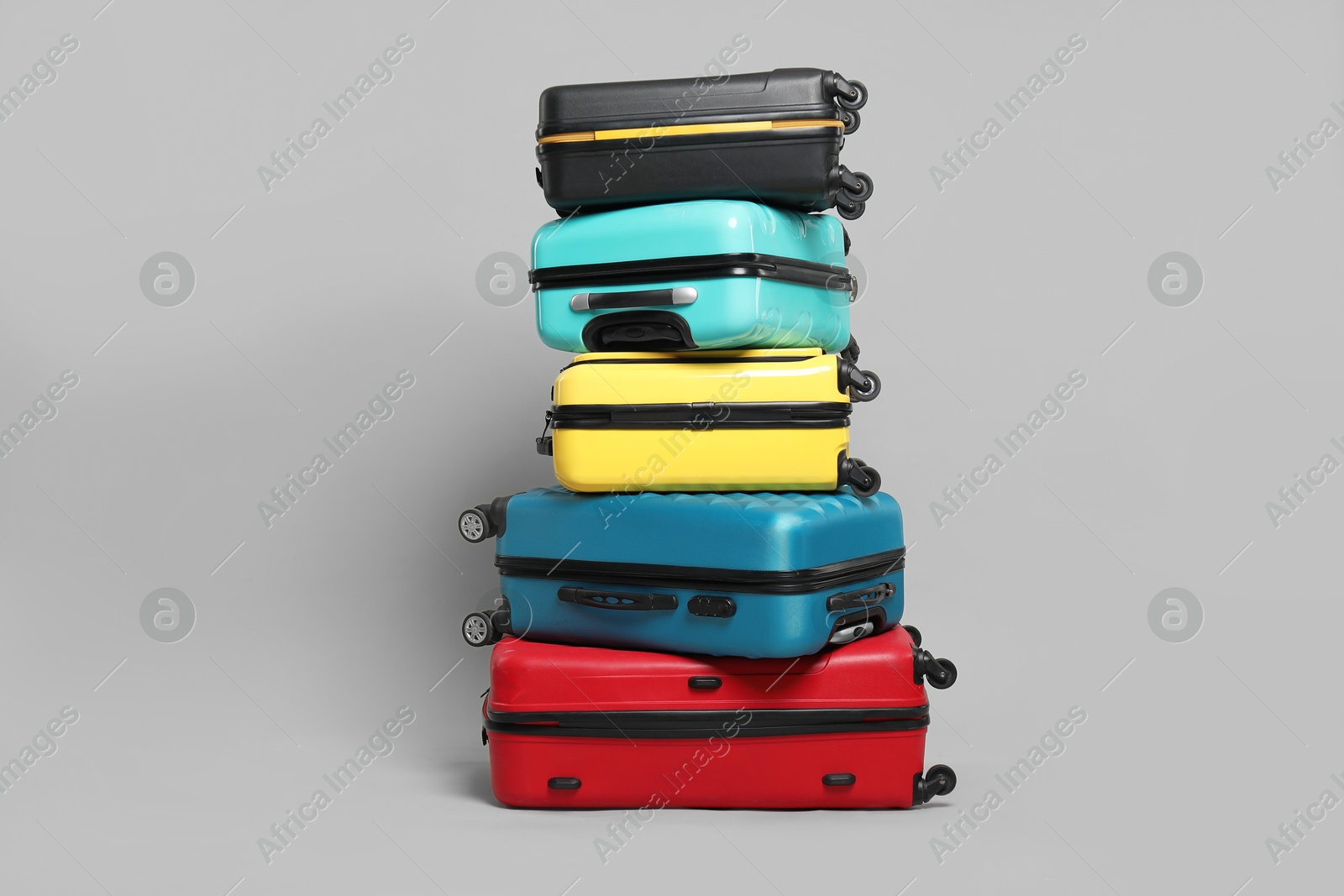 Photo of Stack of colorful suitcases on grey background