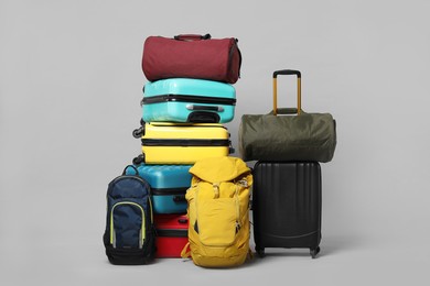 Photo of Stack of colorful suitcases, backpacks and bag on grey background