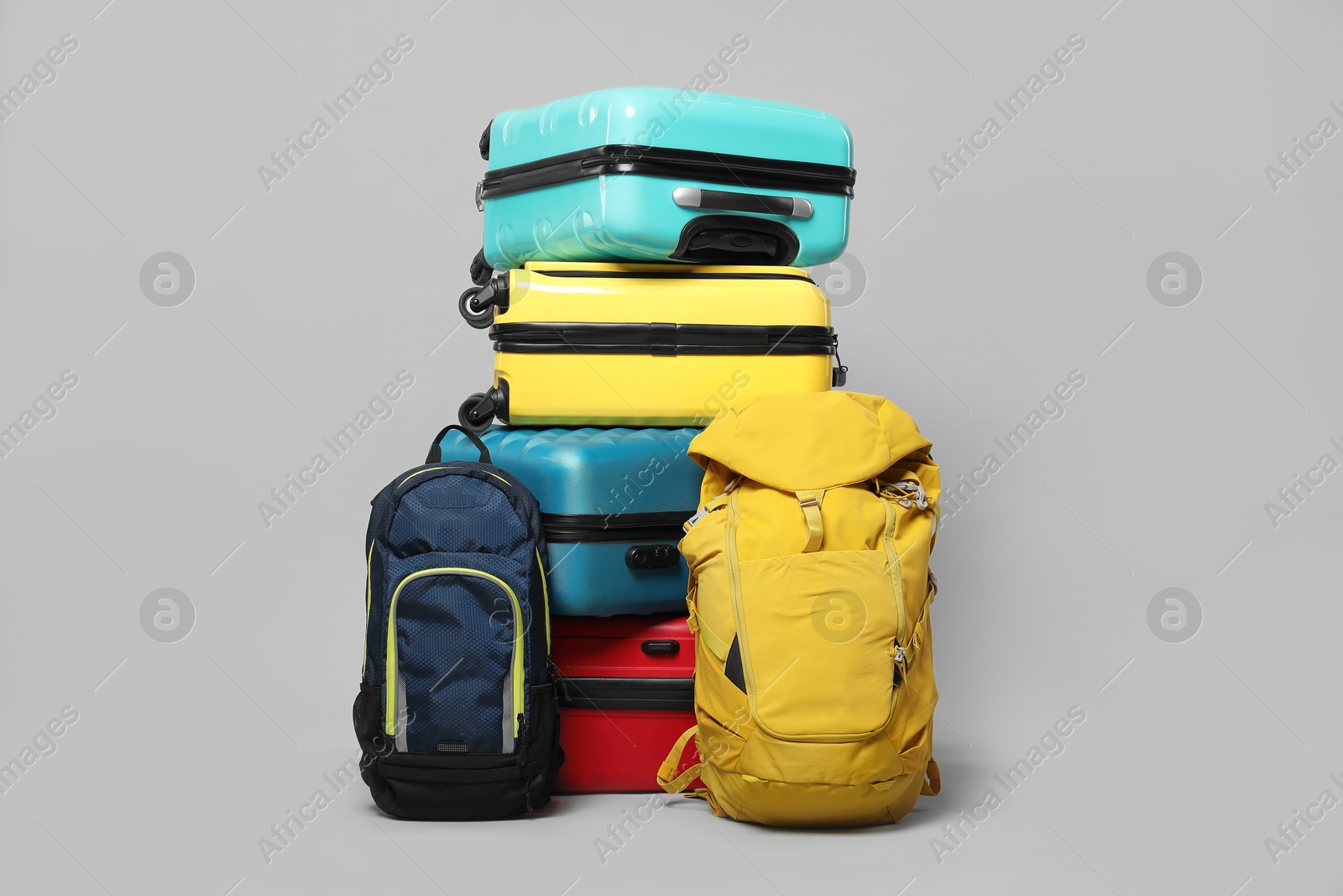 Photo of Stack of colorful suitcases and backpacks on grey background