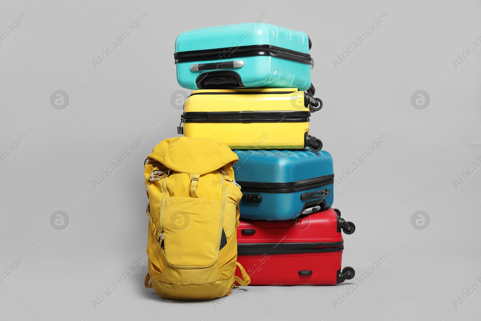 Photo of Stack of colorful suitcases and backpack on grey background