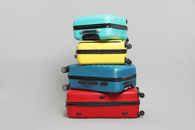 Photo of Stack of colorful suitcases on grey background