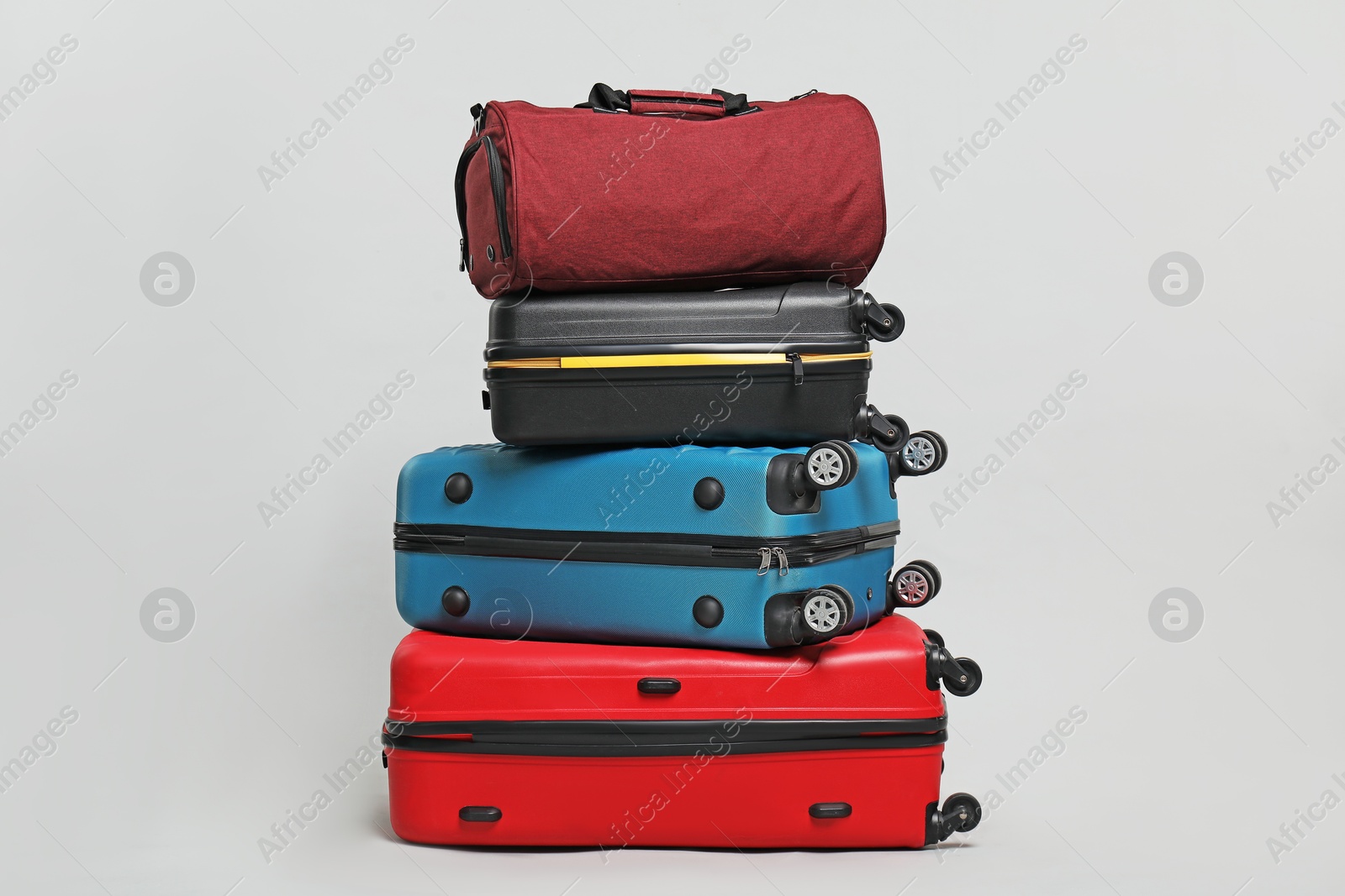 Photo of Stack of colorful suitcases and bag on grey background