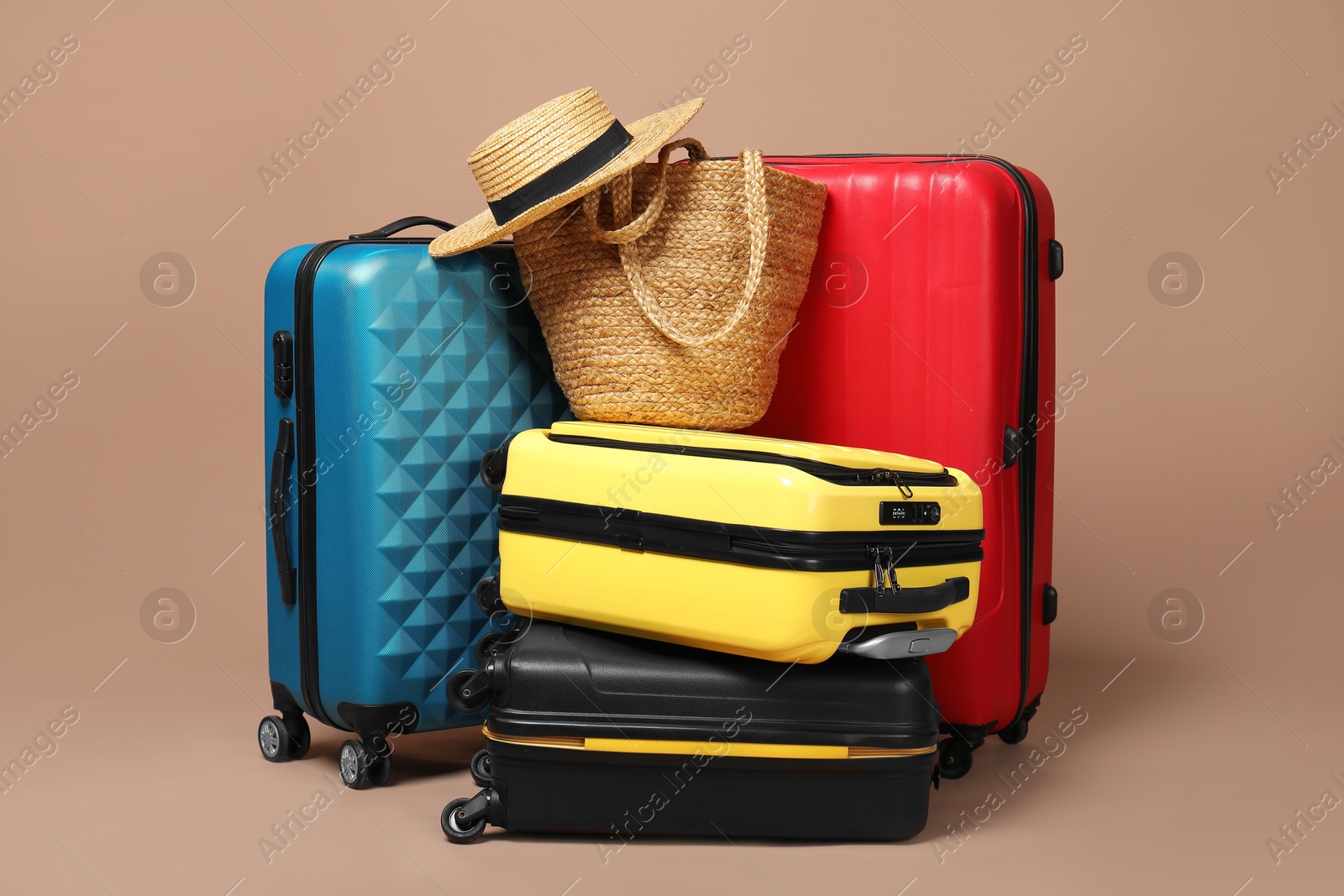 Photo of Many colorful suitcases, beach bag and straw hat on beige background