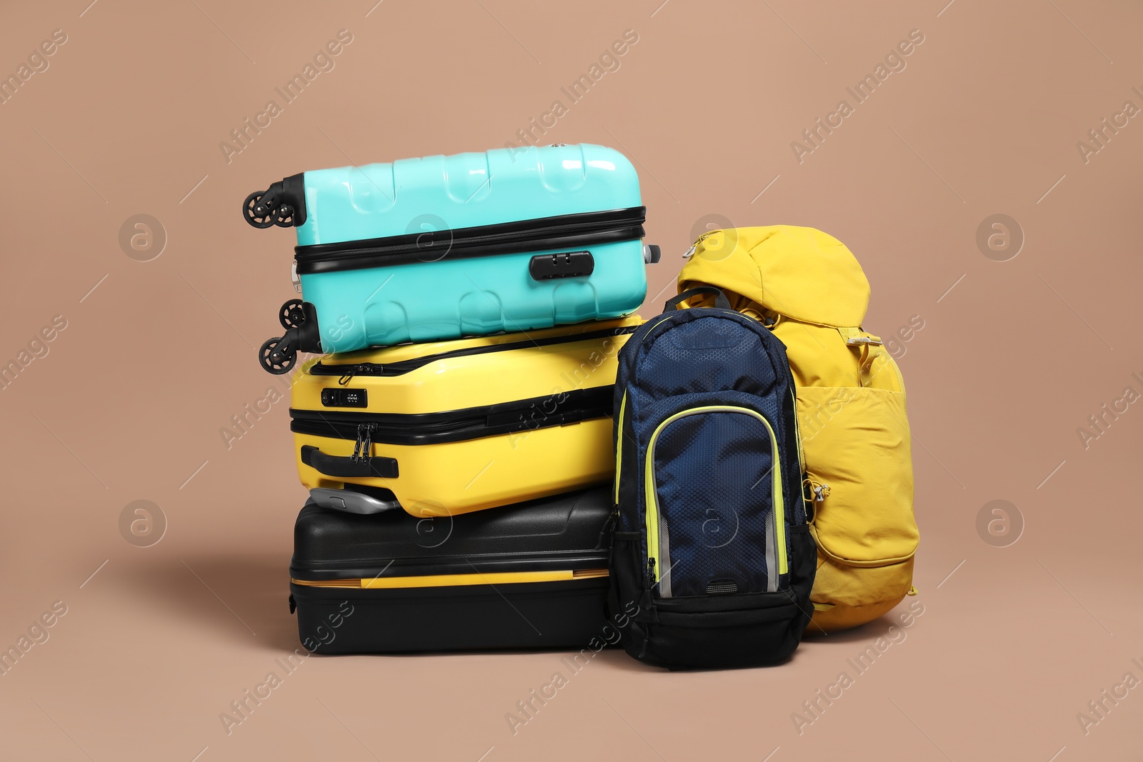 Photo of Stack of colorful suitcases and backpacks on beige background