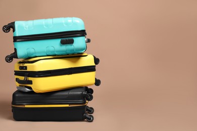 Photo of Stack of colorful suitcases on beige background. Space for text