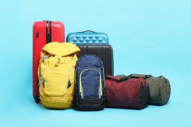 Photo of Colorful suitcases, bags and backpacks on light blue background