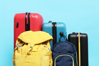 Colorful suitcases and backpacks on light blue background