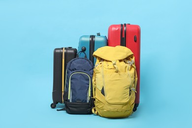 Photo of Colorful suitcases and backpacks on light blue background