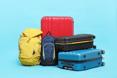 Photo of Colorful suitcases and backpacks on light blue background