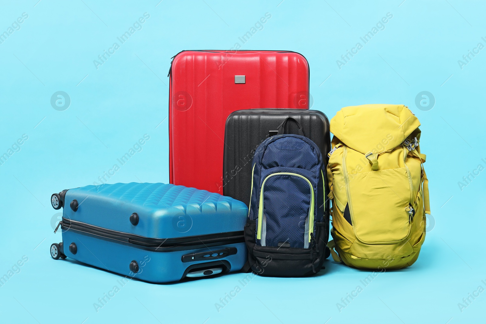 Photo of Colorful suitcases and backpacks on light blue background