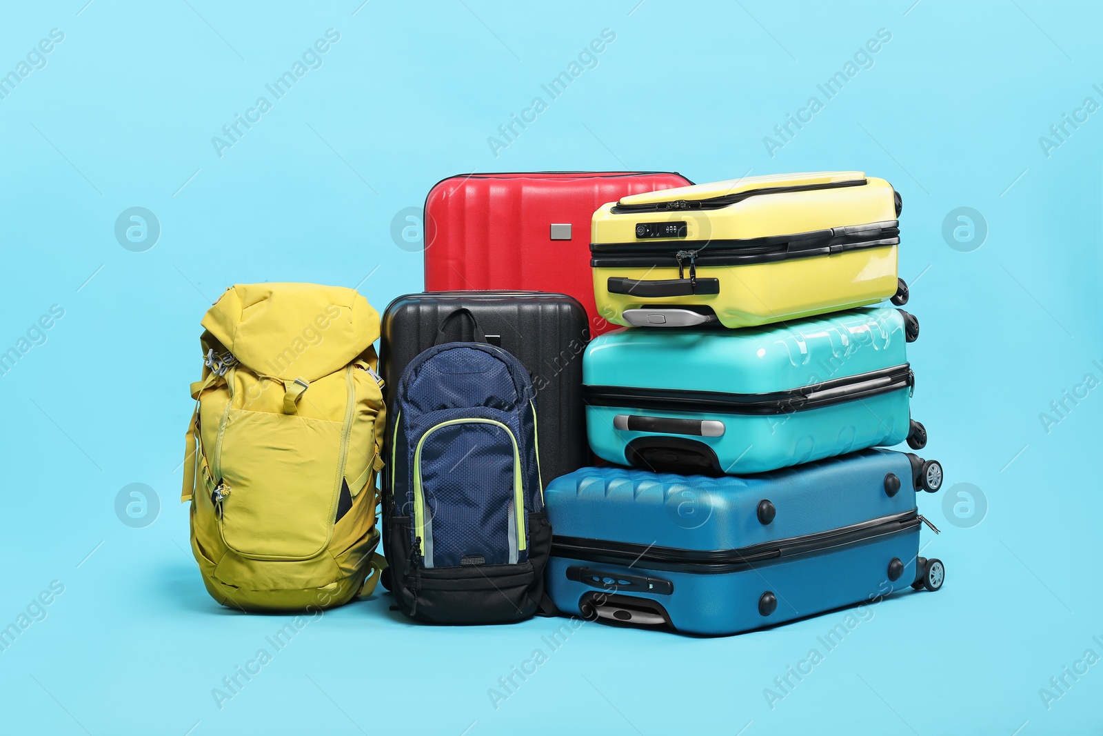 Photo of Colorful suitcases and backpacks on light blue background