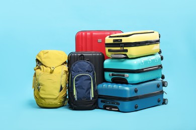 Photo of Colorful suitcases and backpacks on light blue background