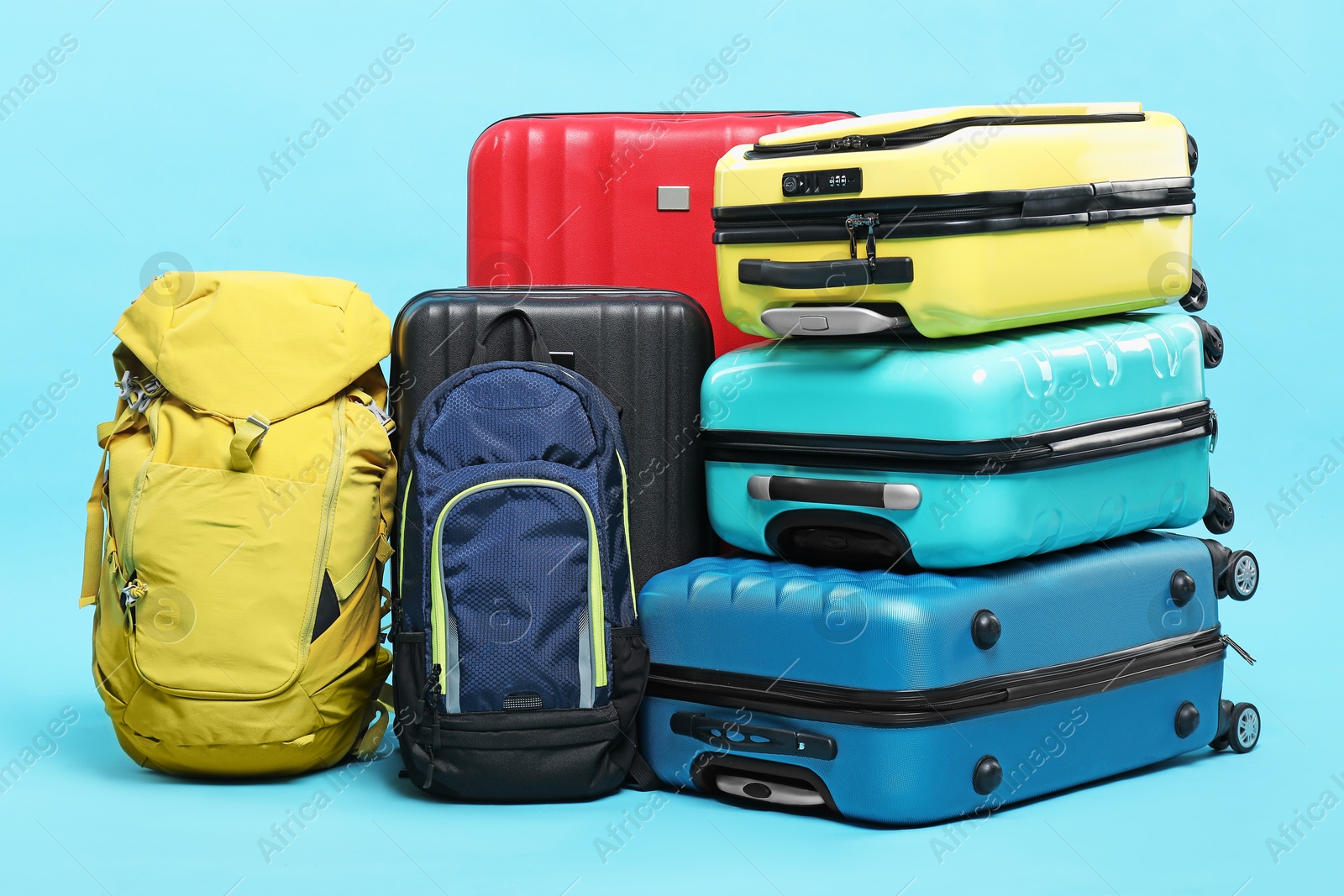 Photo of Colorful suitcases and backpacks on light blue background