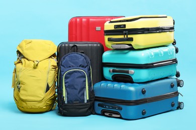 Photo of Colorful suitcases and backpacks on light blue background