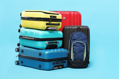 Colorful suitcases and backpack on light blue background