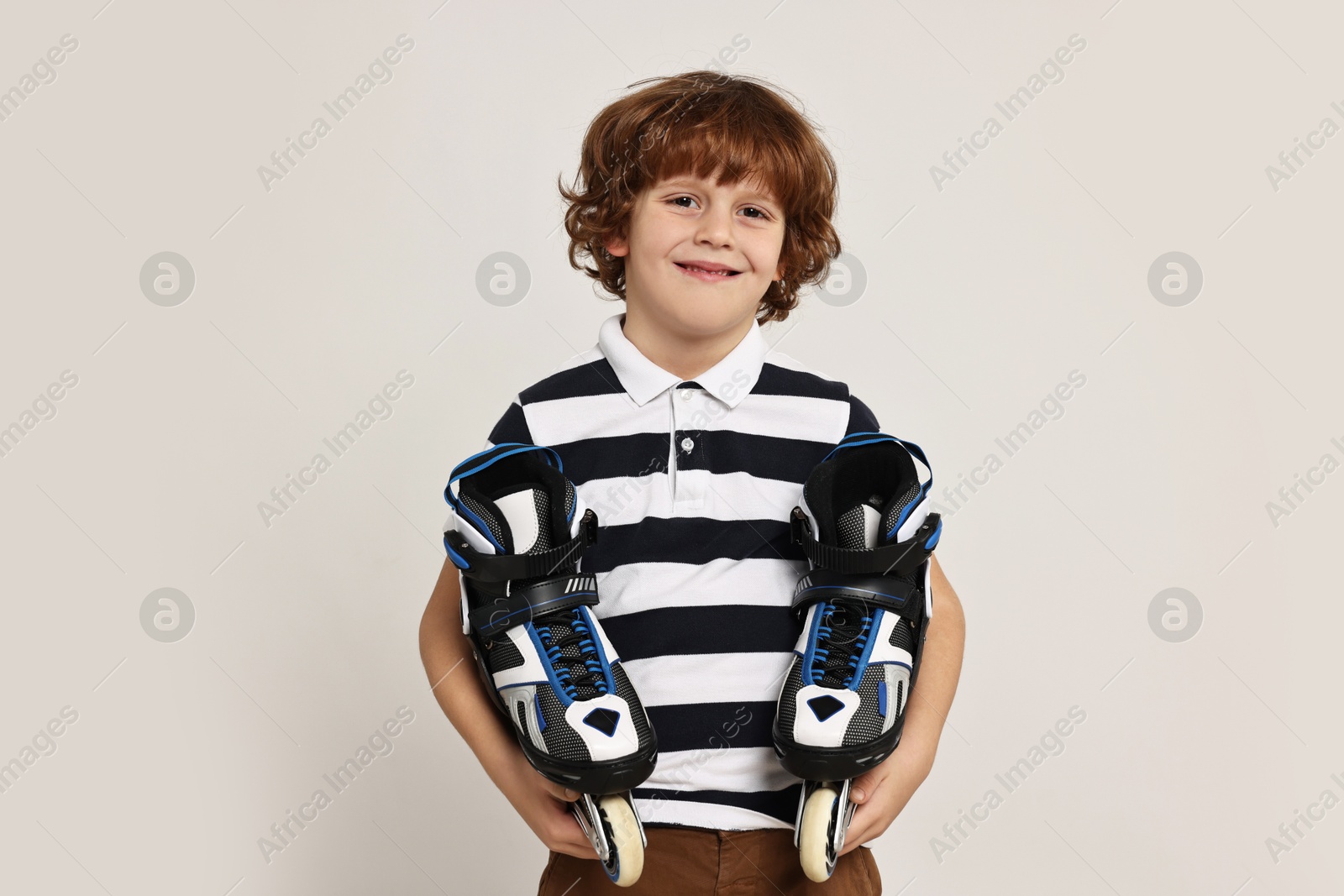 Photo of Little boy with roller skates on light grey background