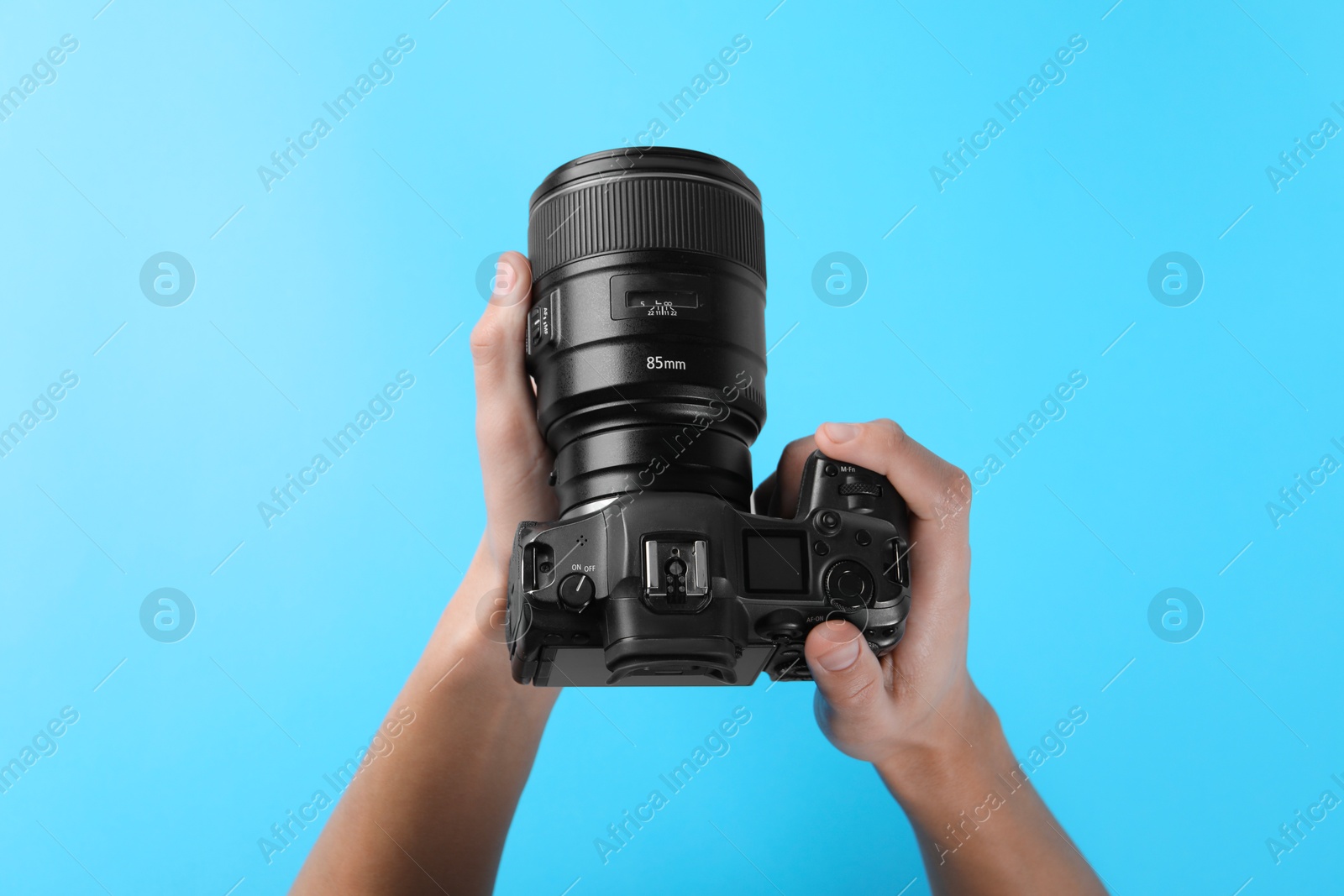 Photo of Photographer with professional camera on light blue background, above view