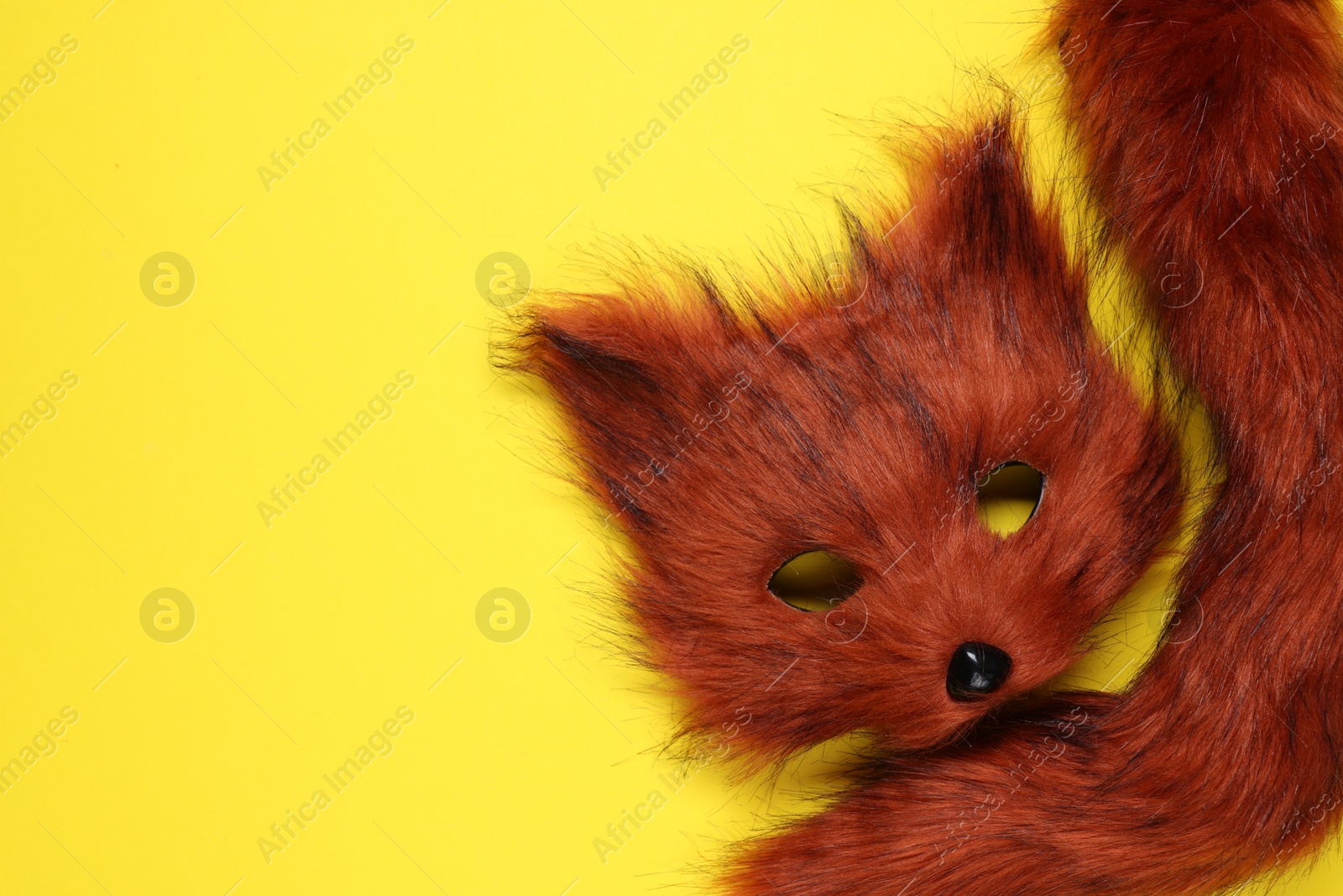 Photo of Quadrobics. Fox mask and tail on yellow background, top view. Space for text