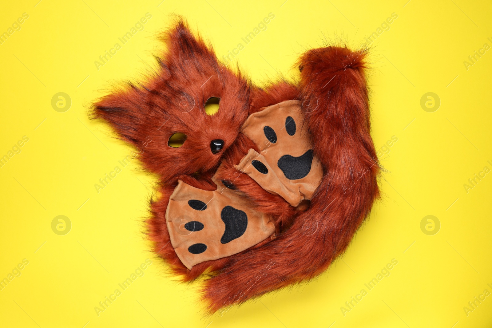 Photo of Quadrobics. Fox mask, tail and gloves on yellow background, top view