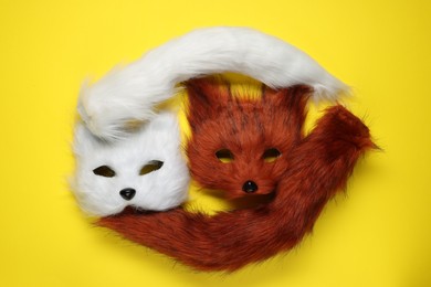 Photo of Quadrobics. Fox and cat masks with tails on yellow background, top view