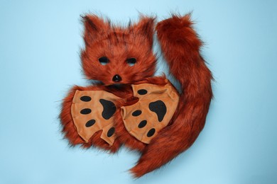 Photo of Quadrobics. Fox mask, tail and gloves on light blue background, top view