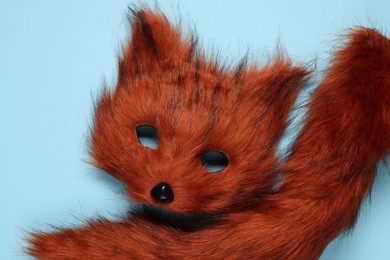 Photo of Quadrobics. Fox mask and tail on light blue background, top view