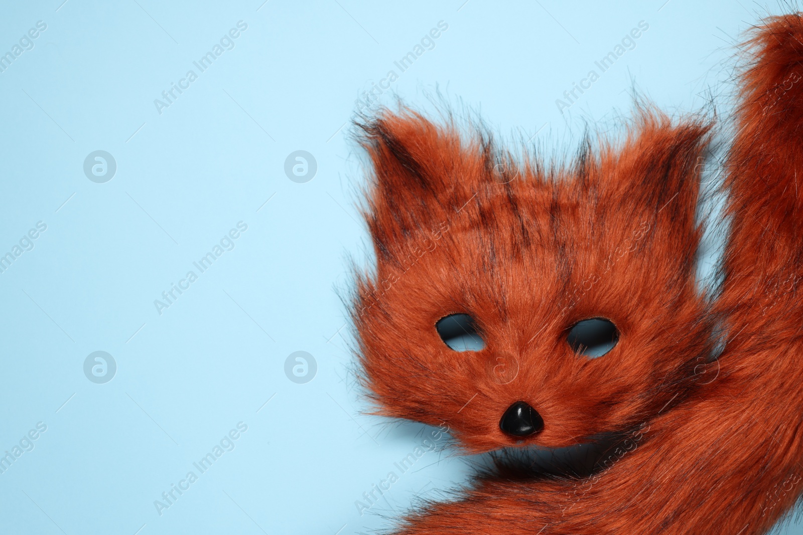 Photo of Quadrobics. Fox mask and tail on light blue background, top view. Space for text