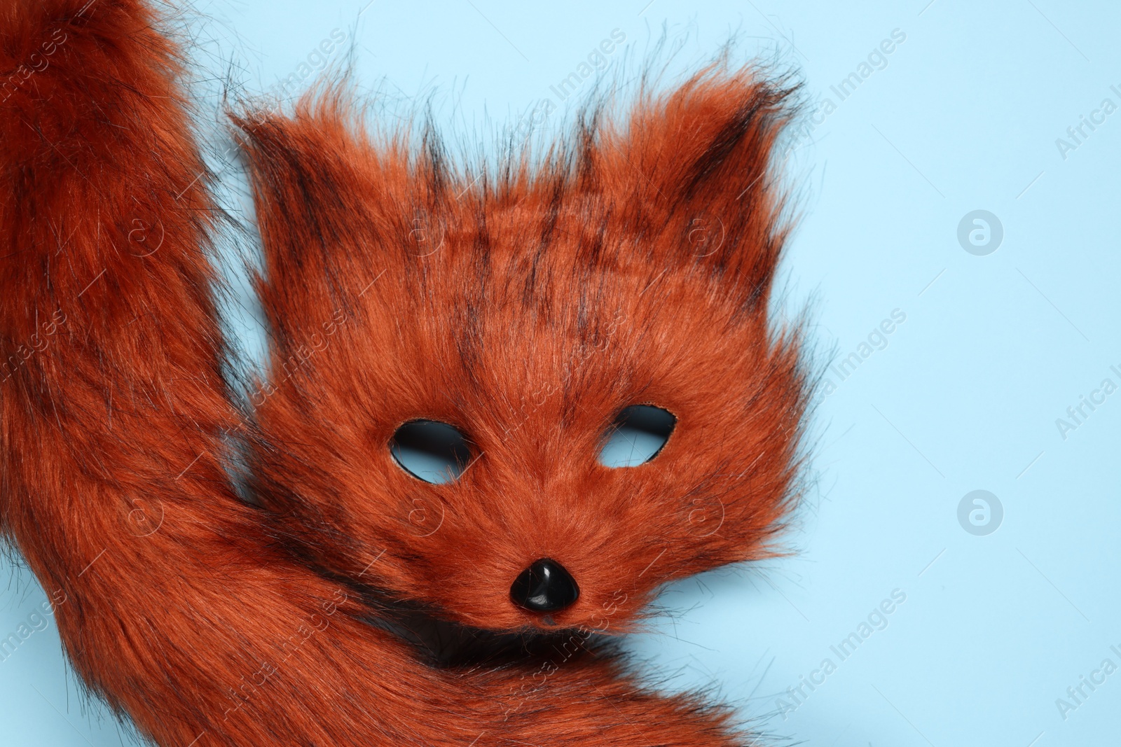 Photo of Quadrobics. Fox mask and tail on light blue background, top view