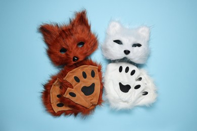 Photo of Quadrobics. Fox and cat masks with gloves on light blue background, top view