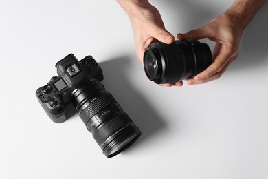 Photo of Photographer with camera and lens on light background, top view