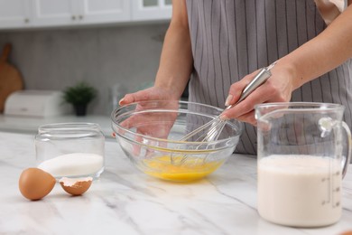 Photo of Woman making dough at white marble table indoors, closeup