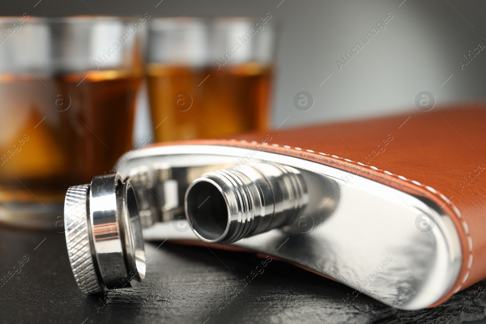 Photo of Hip flask and glasses of whiskey on table, selective focus