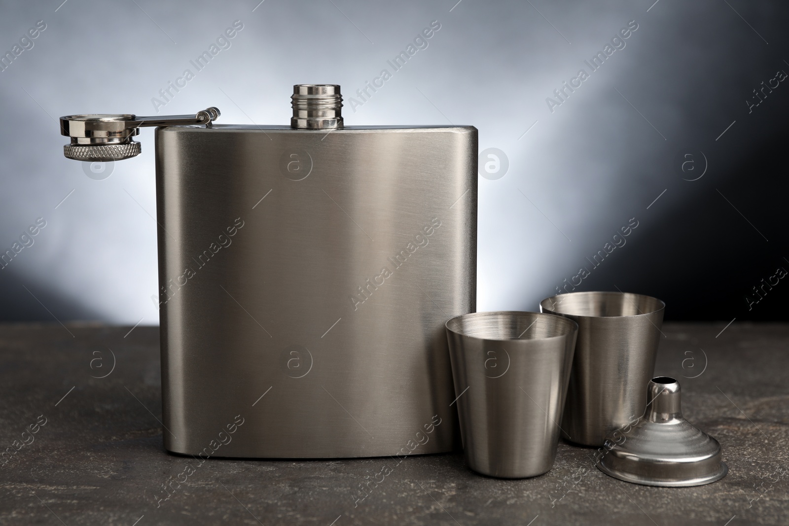 Photo of Hip flask, cups and funnel on grey table