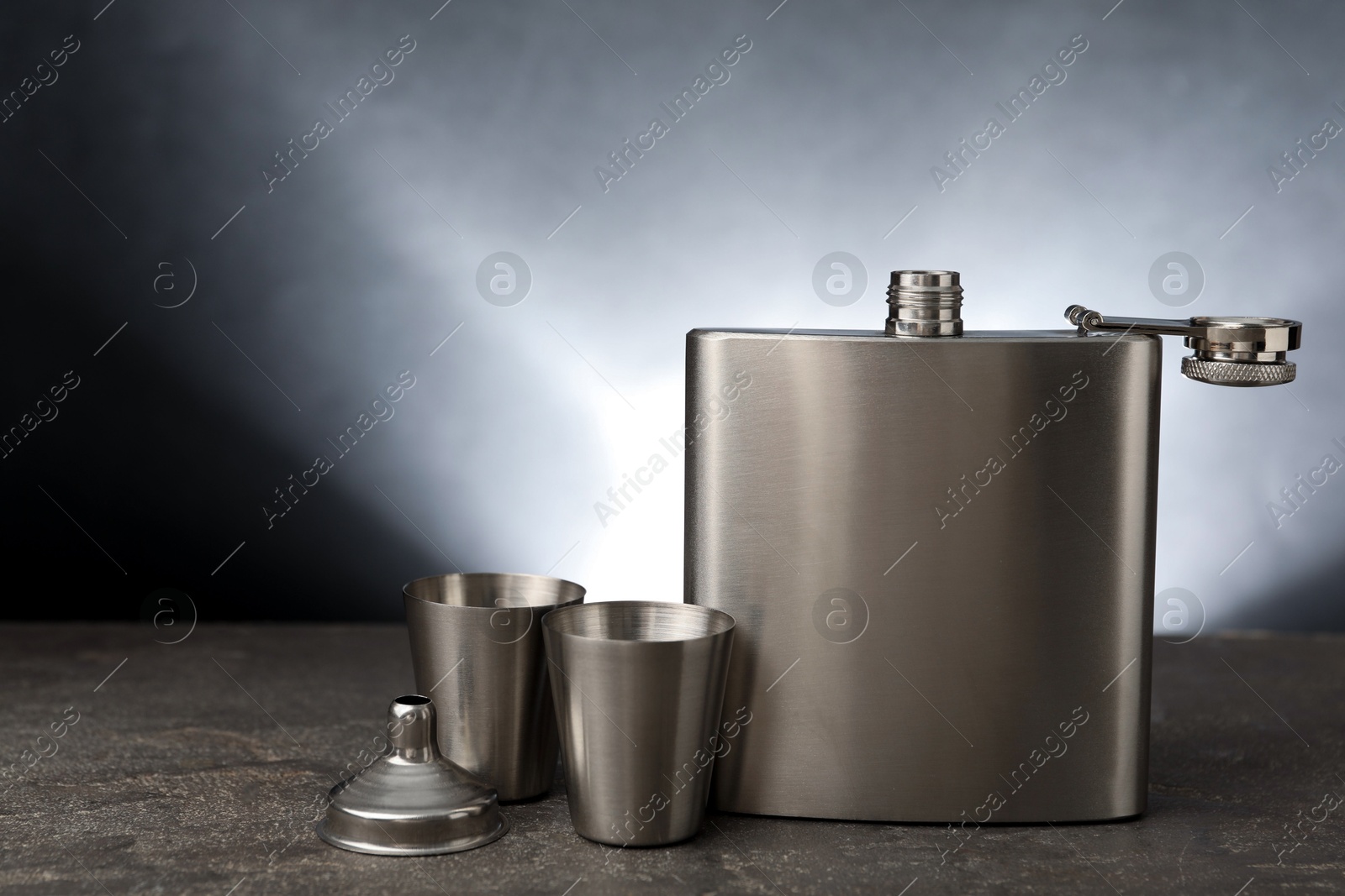 Photo of Hip flask, cups and funnel on grey table, space for text