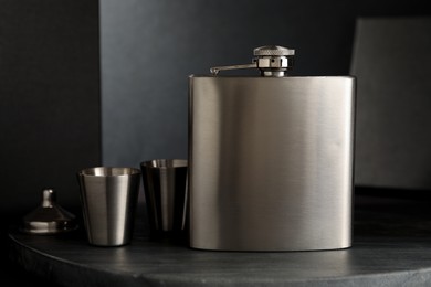 Photo of Hip flask, cups and funnel on table, closeup