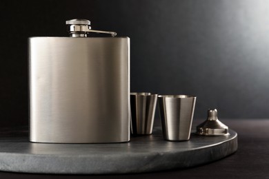 Photo of Hip flask, cups and funnel on wooden table, closeup