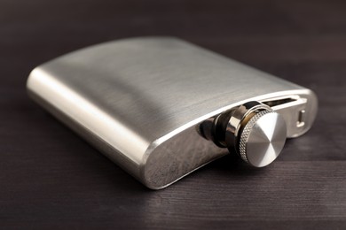 Photo of One hip flask on wooden table, closeup