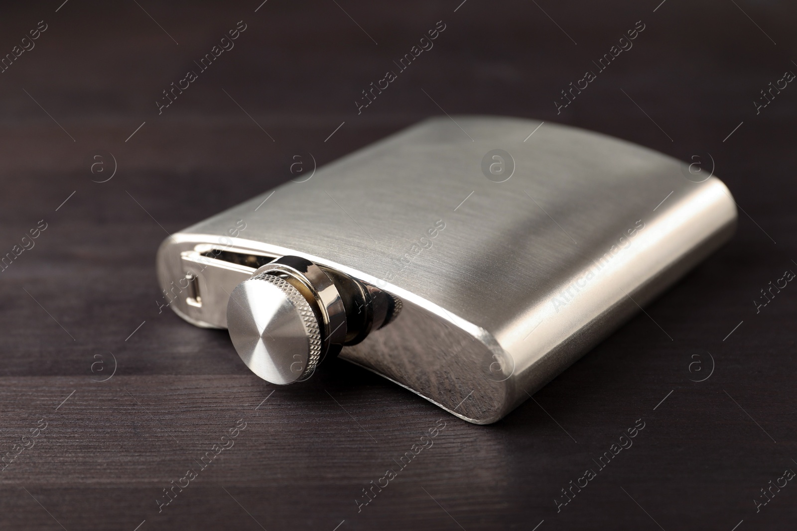 Photo of One hip flask on wooden table, closeup