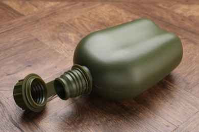 Photo of Green plastic canteen on wooden table, closeup