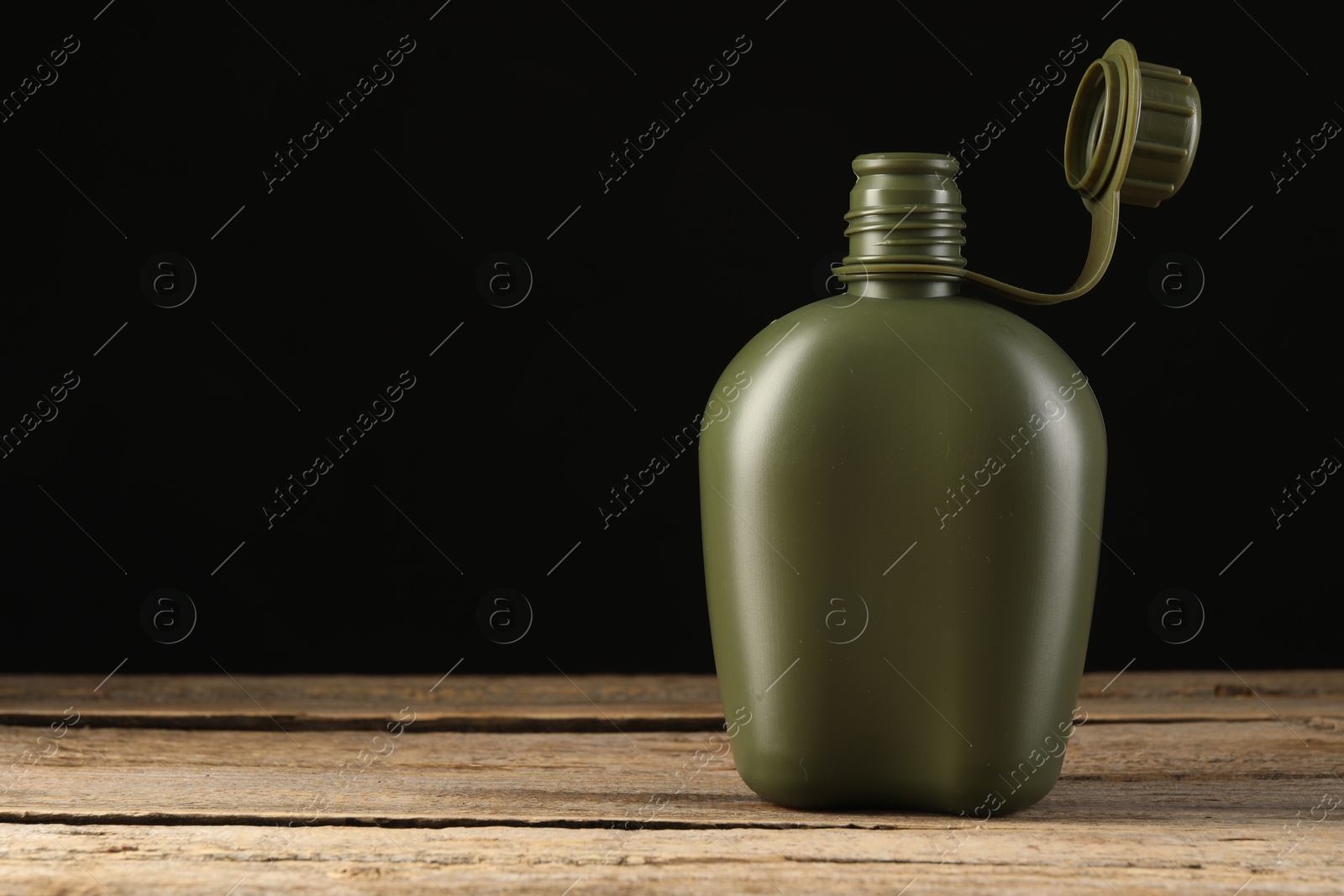 Photo of Green plastic canteen on wooden table, space for text