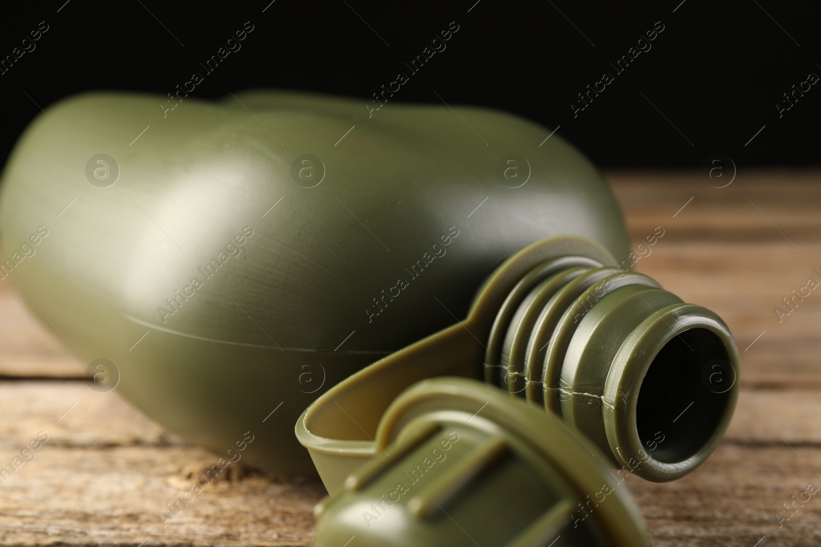 Photo of Green plastic canteen on wooden table, closeup