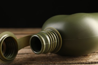 Photo of Green plastic canteen on wooden table, closeup