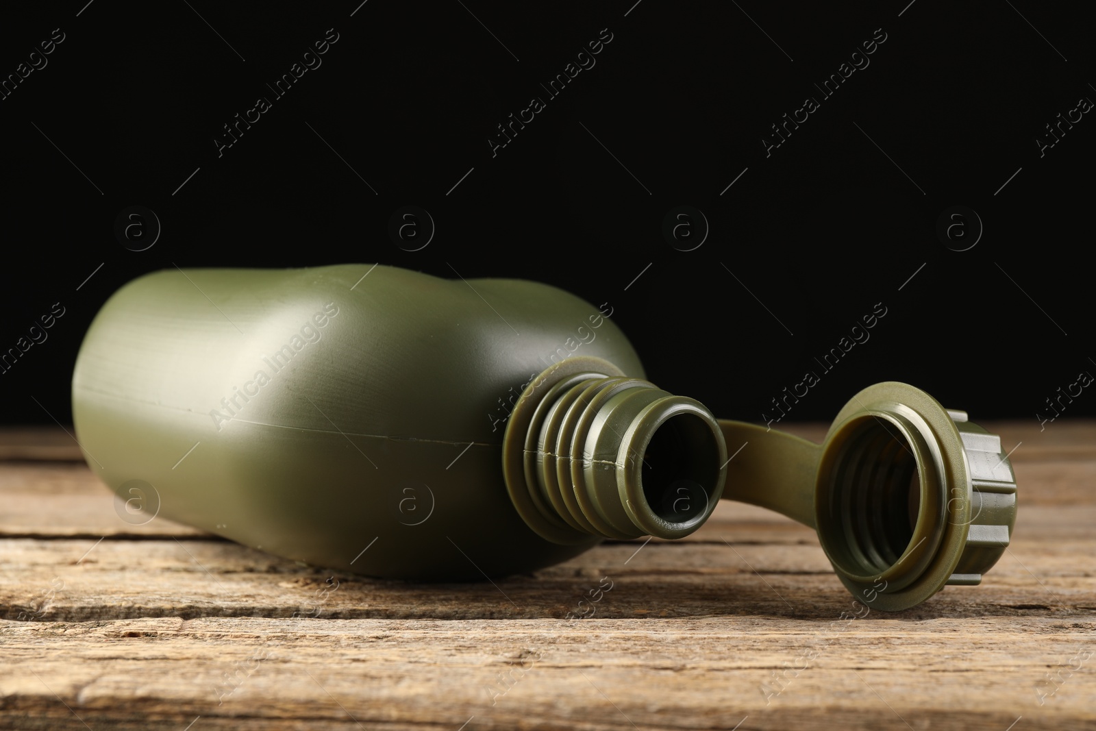 Photo of Green plastic canteen on wooden table, closeup