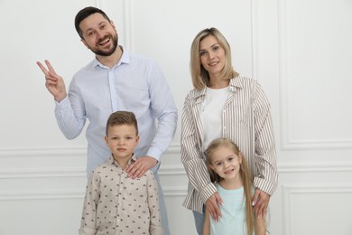 Happy parents and their children near white wall indoors