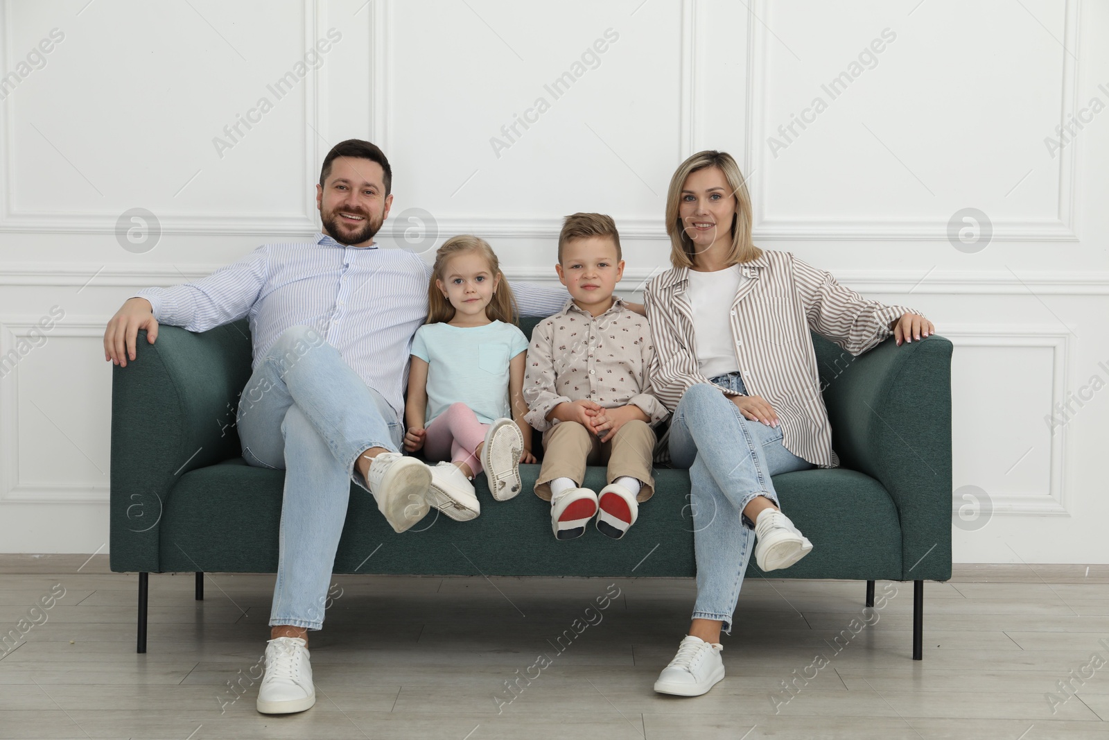 Photo of Happy parents and their children on sofa at home