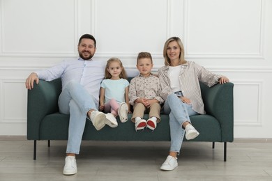 Happy parents and their children on sofa at home