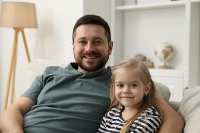 Photo of Happy father and his cute little daughter on sofa at home